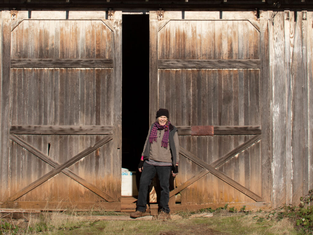 Cindy Lou Evans Pease, owner of Evans Farms LLC, stands in front of the barn designed by her father, Eldon Evans, when he was just 17 years old. Photo by Peter Szymczak